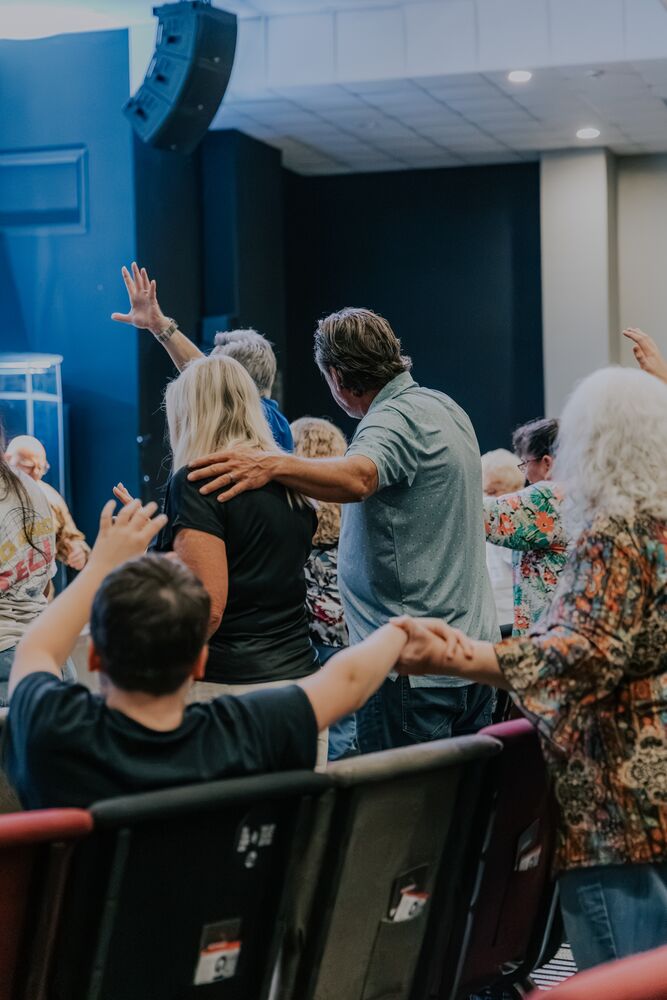 People praying together with hands raised at Pathway Church
